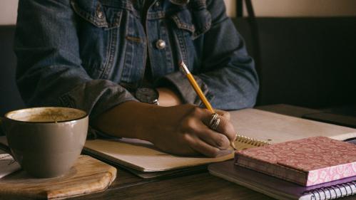 Woman writing with a pencil in a notebook
