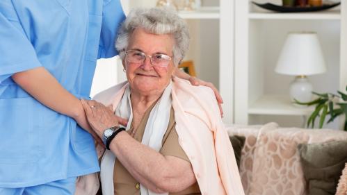 An image of an elderly woman holding hands with her nurse