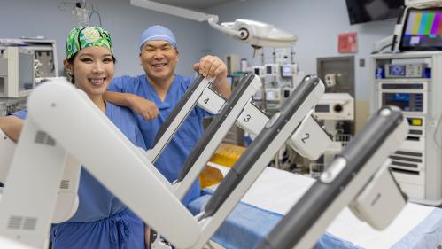 surgeons pose with surgical robot