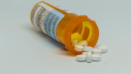 White pills spill out prescription bottle