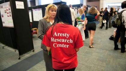 Photo of past symposium with student's back wearing red t-shirt that reads Aresty Research Center