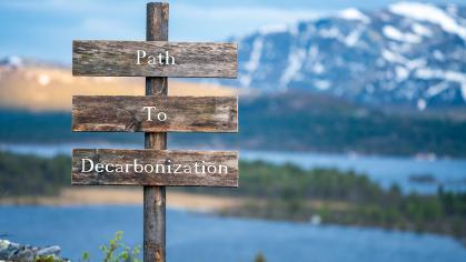 path to decarbonization text quote on wooden signpost outdoors in nature during blue hour.
