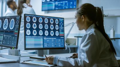 Female Medical Research Scientist Working with Brain Scans on Her Personal Computer, Writing Down Data in a Clipboard. Modern Laboratory Working on Neurophysiology, Science, Neuropharmacology.