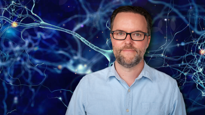 Michael Cole standing in front of image of neural synapses 