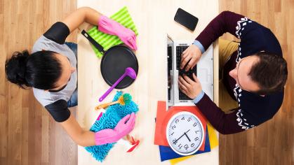 An image of a man and a woman, sitting face to face, the woman with household items and the man with work related items depicting gender bias