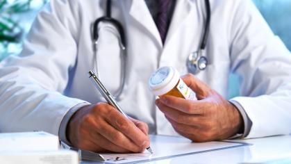 A doctor in a white lab coat writing down a prescription