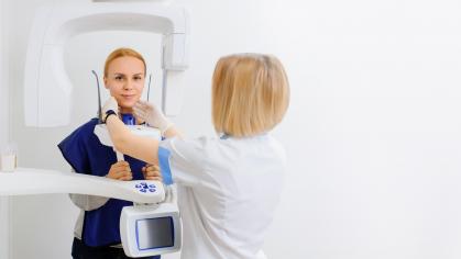 A dental x-ray doctor is making to a young female patient a digital dental x-ray panoramic radiography orthopantomography of the oral cavity.