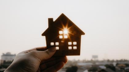 A cut out of a model home held up in a person's hand. 