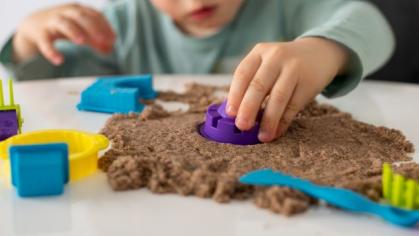 image of pre-k kid playing with sand and figures