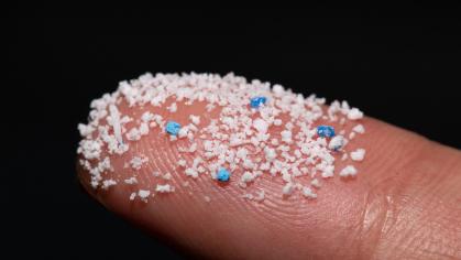 Micro plastic .Small Plastic pellets on the finger.