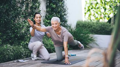 Older woman doing light exercise with an aide