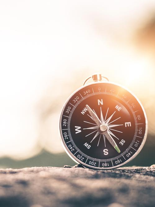 picture of a compass with the sun behind it