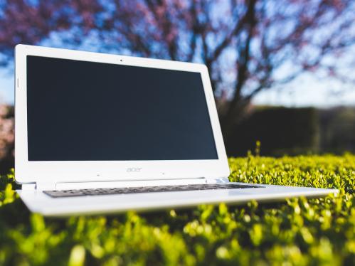 Laptop with blank screen on grass