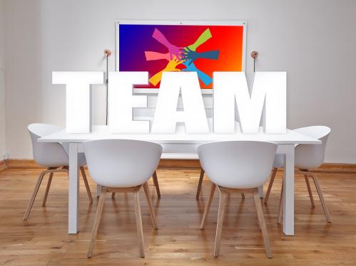 White conference room table with large TEAM in block letters on top   