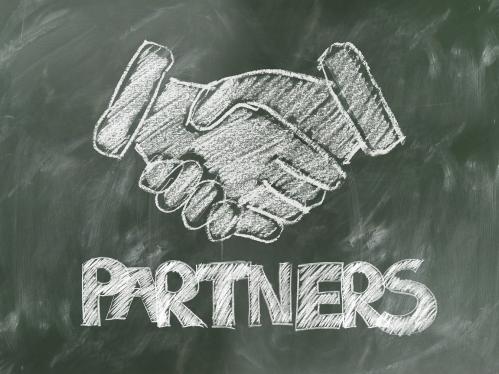 A chalkboard drawing of shaking hands with Partners written underneath in capital letters