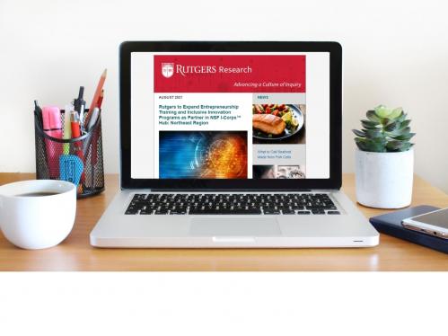 Laptop on a desk with Rutgers Research Newsletter on screen, coffee mug and pencil holder on left and succulent plant and mobile phone on the right