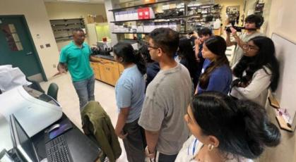 High school students conduct video interview of graduate student in a research laboratory