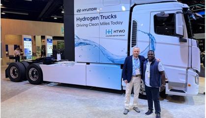Two men stand in front of the front part of a new truck