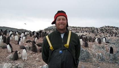 Man standing in field with penguins behind him