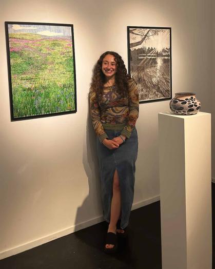 Rutgers graduate Serafina Kennedy poses between two framed works of art.