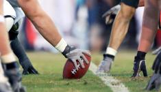 Football player lined up to hike the ball on field.
